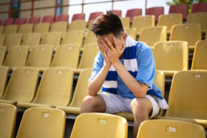 sad athlete in the blue/white jersey on the yellow stadium seats